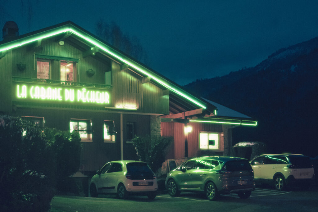 Photographie de paysage nocturne de la façade d'un restaurant où les néons vert illumine la scène.